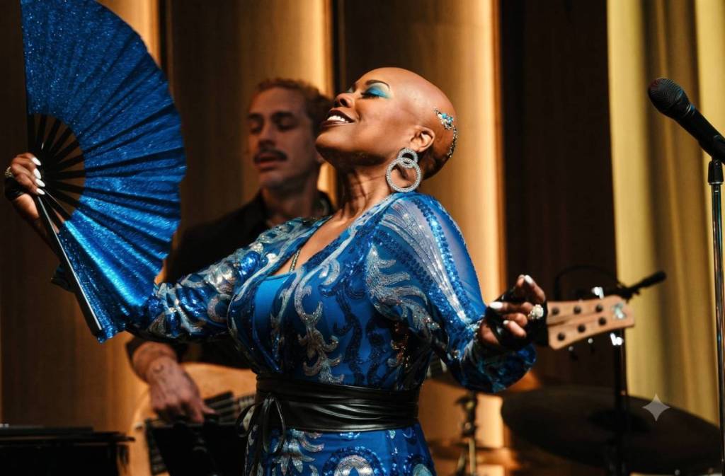 a woman from Prince's backing group singing on stage in a sparkly blue outfit