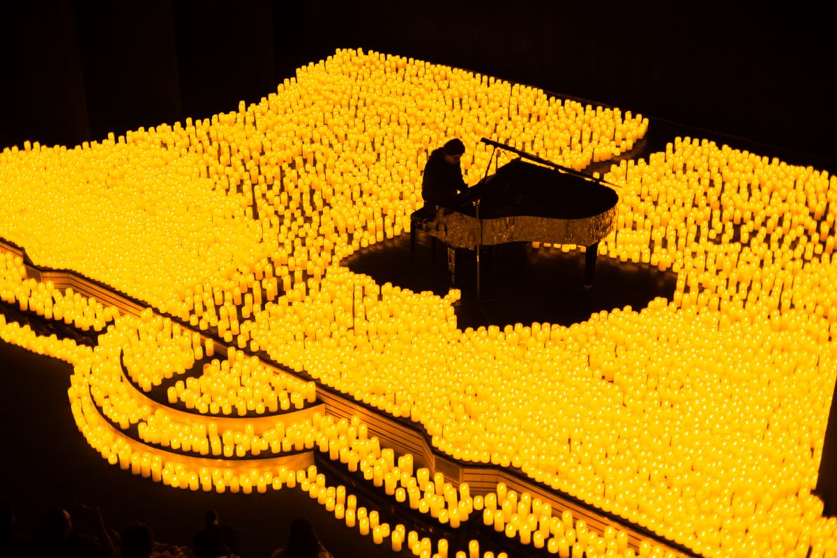 Klavierspieler spielt auf der Bühne von einem Candlelight-Konzert auf einem Flügel, umgeben von zahlreichen Kerzen