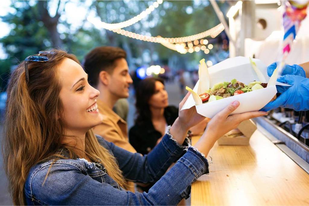 Eine junge Frau bekommt Essen an einem Street Food Stand in Köln.