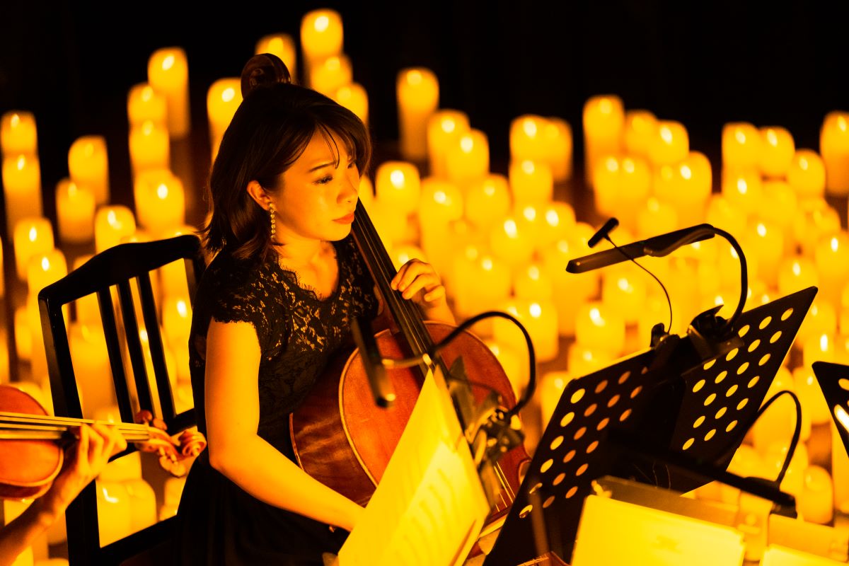Musikerin spielt bei einem Candlelight-Konzert auf der Bühne, umgeben von zahlreichen Kerzen im Hintergrund