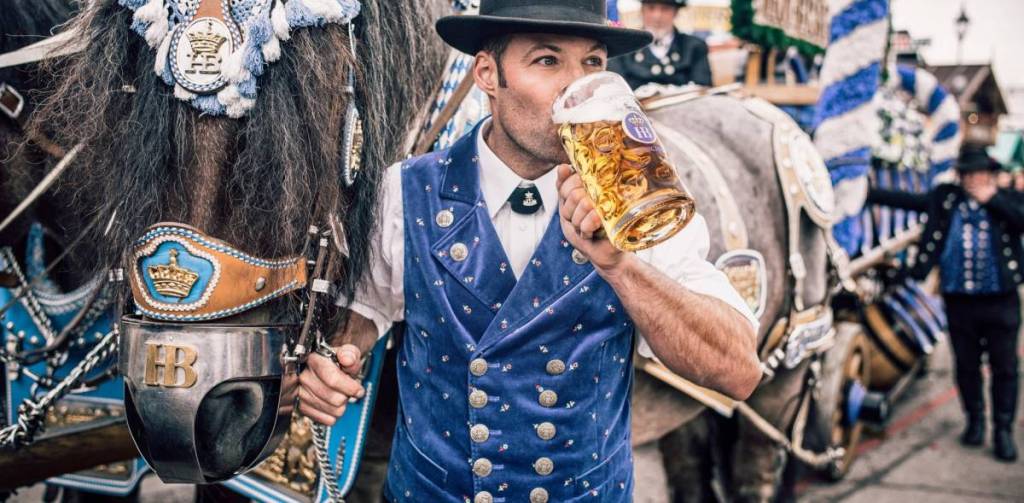 un hombre junto a un caballo bebiendo cerveza alemana
