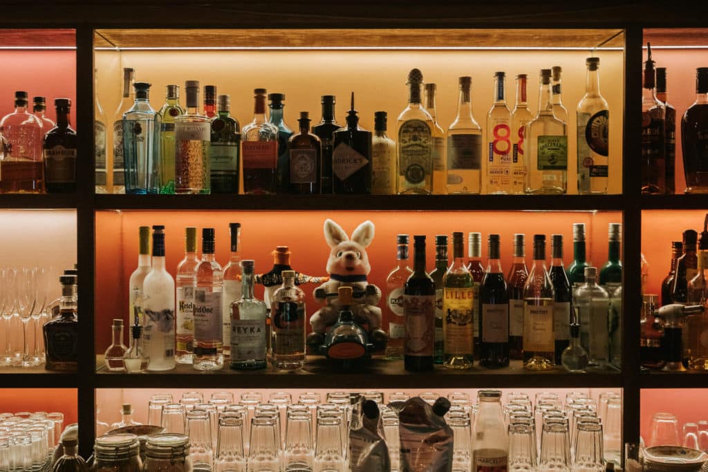 a vast selection of spirits on shelving above glases, with a stuffed animal in the middle of it all, from Little Yellow Door - one of the London Cocktail Week bars
