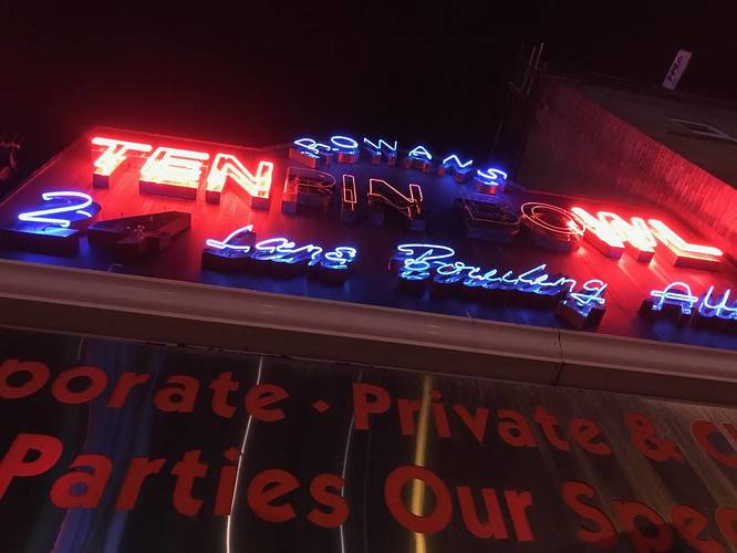 a neon sign for 'rowan's ten pin bowling' with some letters not illuminating properly