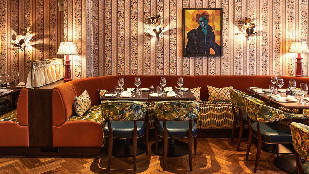 the eclectic interiors of julies, with funky wallpaper, abstract artwork, and patterned chairs and banquette seating