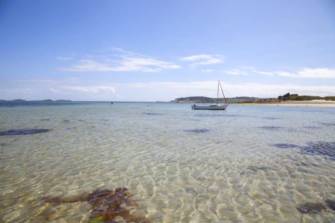 Crystal-clear waters and a docked yacht at Pentle Bay in Tresco, the Scilly Isles
