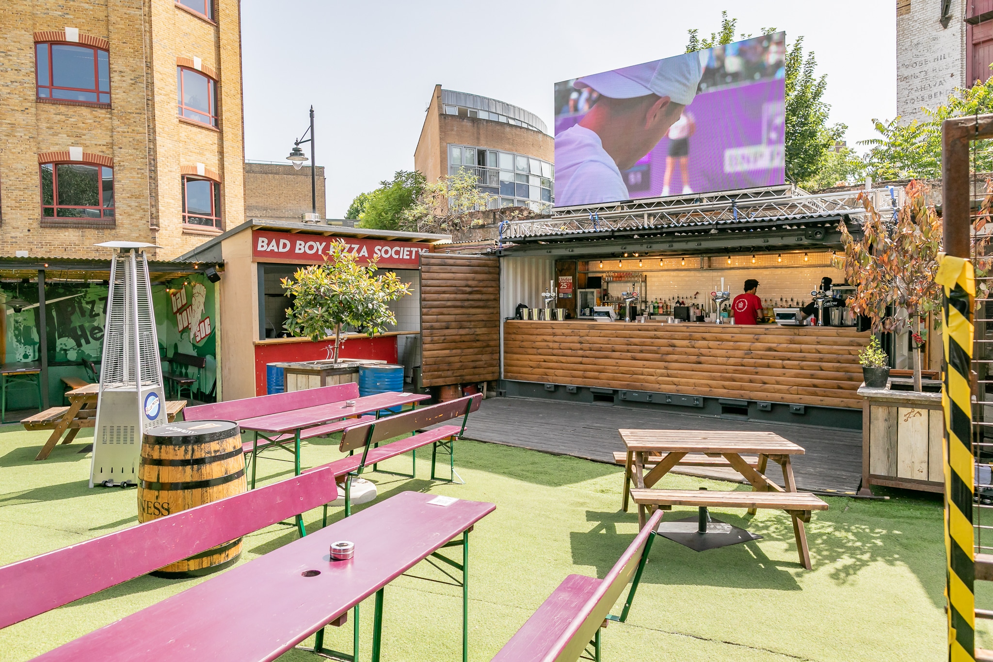 A shot of the Vinegar Yard viewing area, tables and seats are arranged in the area next to the bar, atop which a screen shows the Wimbledon action