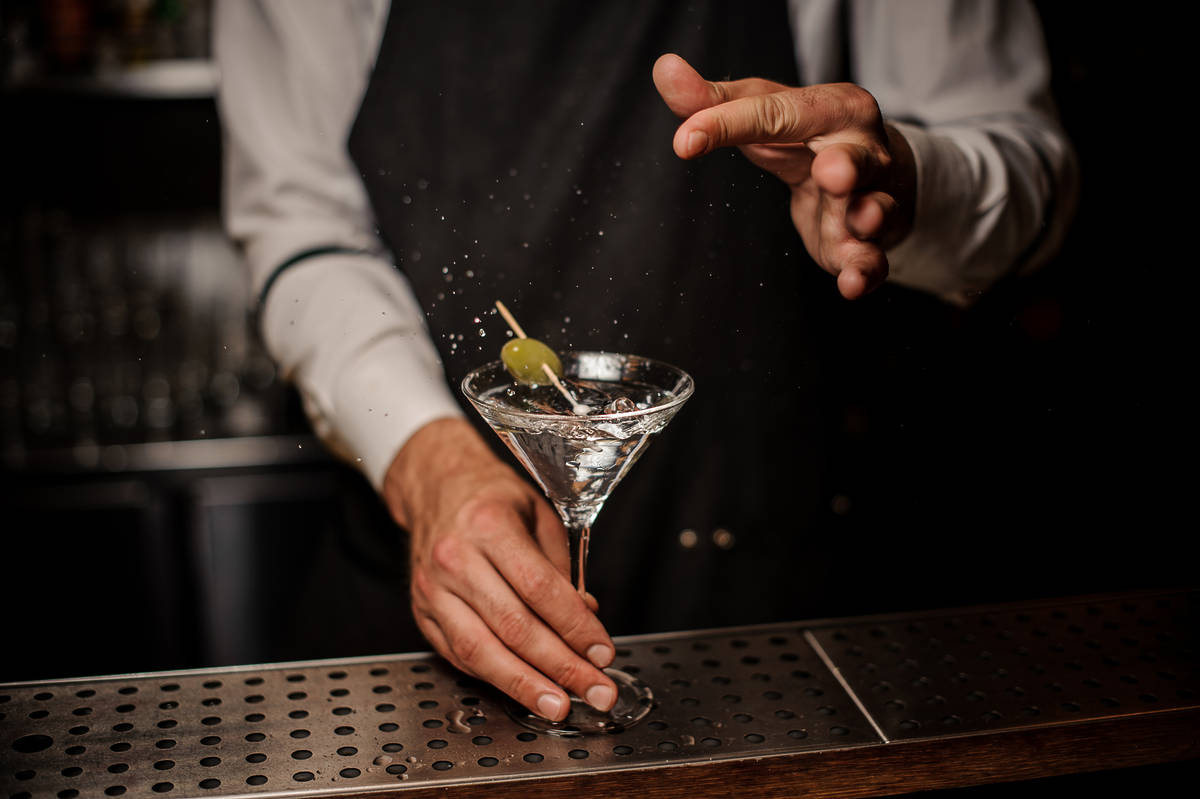 a bartender throwing an olive into a martini