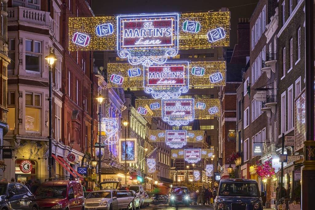 le luci natalizie a forma di striscione che di notte si estendono da un edificio all’altro sopra St Martins Lane