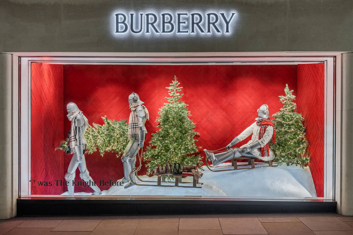 the window for a burberry shop, with a christmassy scene, featuring christmas trees and someone riding a sleigh