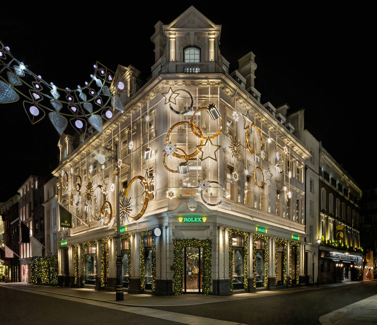 the exterior of a rolex shop lit up by a swirling white and gold christmas lights display