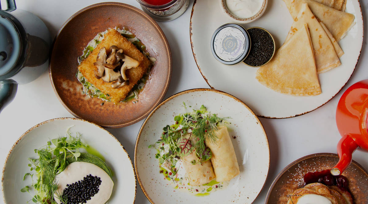 an array of russian dishes, including caviar and pancakes, russian dumplings, and more