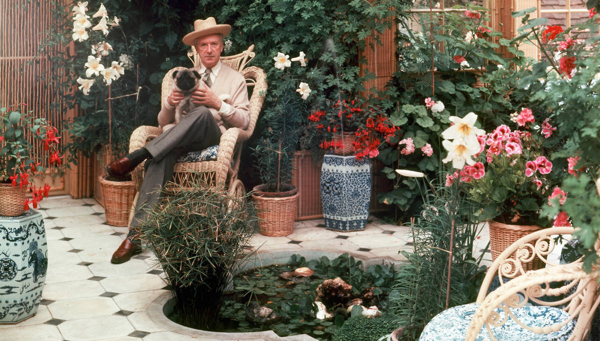 cecil beaton sitting in a garden full of flowers