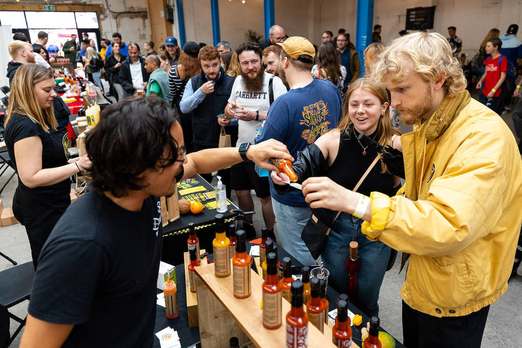 Dos personas prueban un poco de salsa picante en el festival Hot Sauce Society