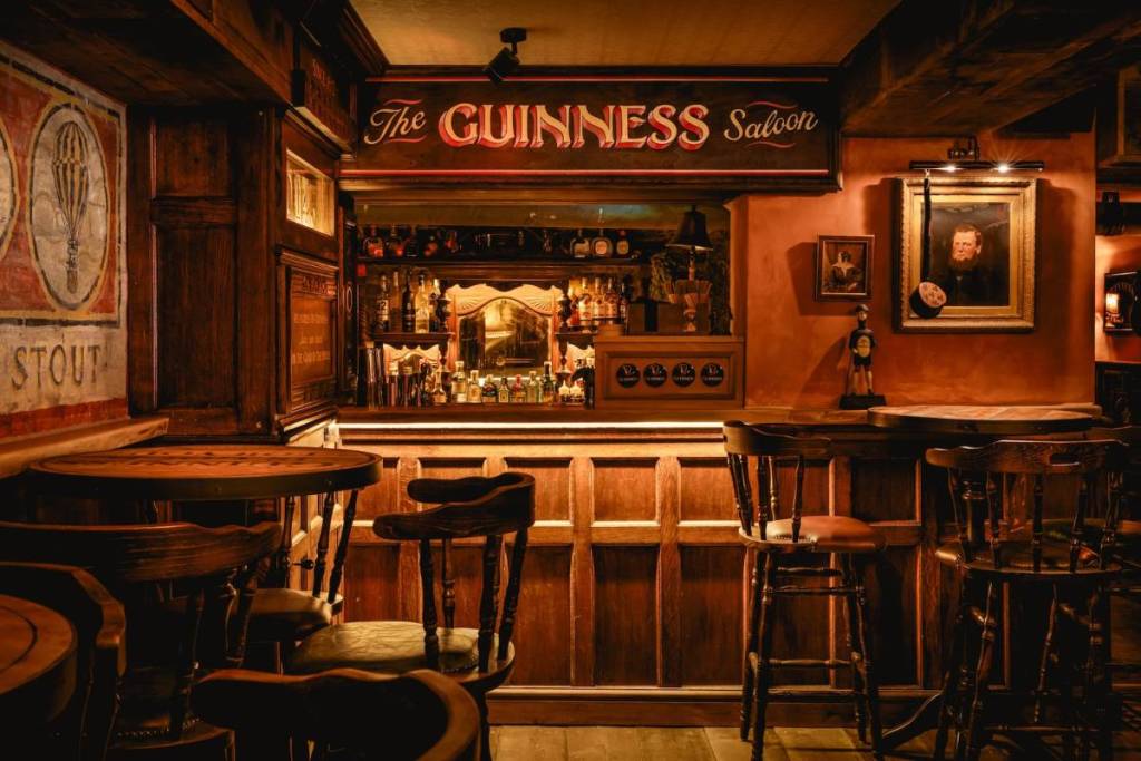 o interior do bar Mr Foggs Market Tavern, inspirado na era vitoriana, com um recanto revestido a madeira que exibe uma placa com uma inscrição à moda antiga a dizer «the Guinness Saloon»