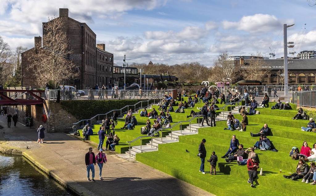 Les gens s'assoient sur les marches vertes entre Canal Square et Granary Square à King's Cross