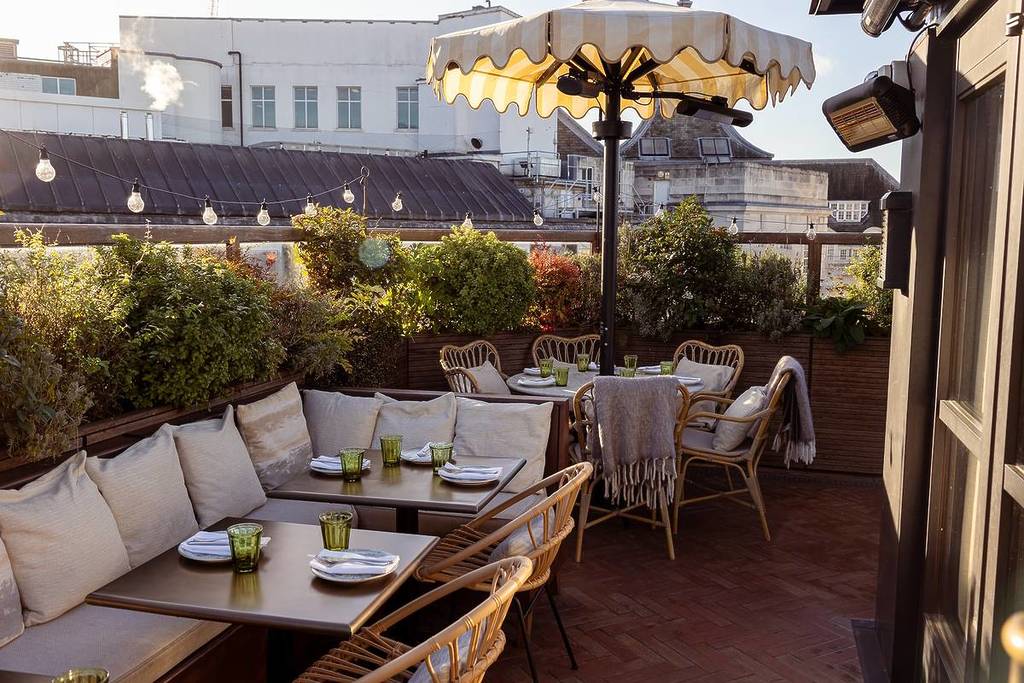 la terrasse panoramique du restaurant Yasmin au crépuscule, avec ses chaises en bambou, son parasol festonné et ses plantes luxuriantes