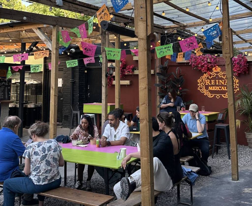 people sit at colourful tables drinking under Mexican-inspired decor