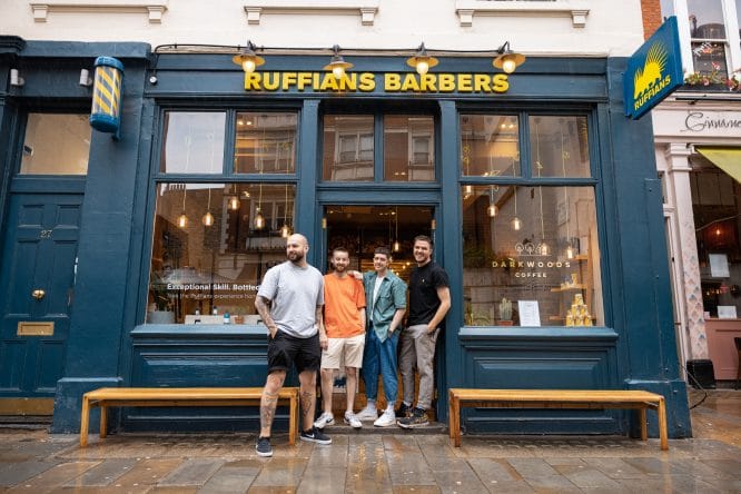 The team posing outside Ruffians barbers shop in London, England