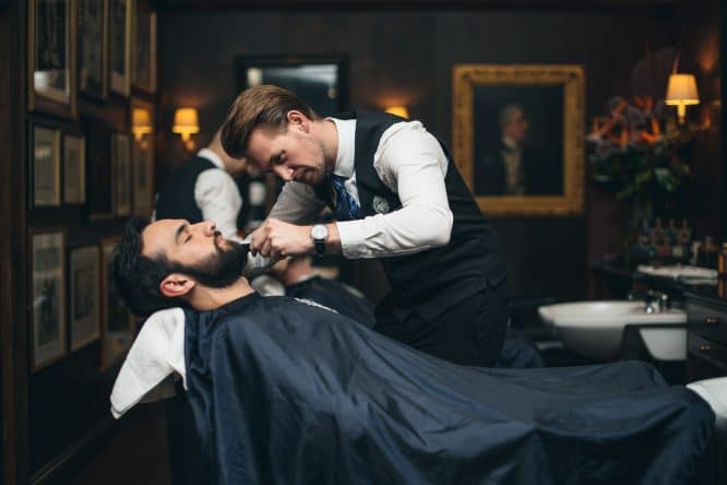 A barber shaving someone's beard at Truefitt & Hill