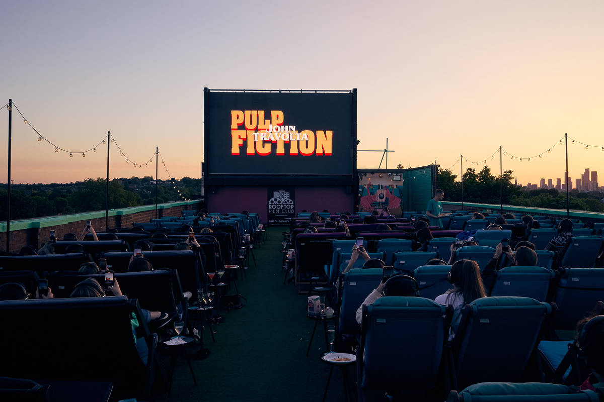 pulp fiction being screened on a huge screen on a london rooftop as the sun starts to set