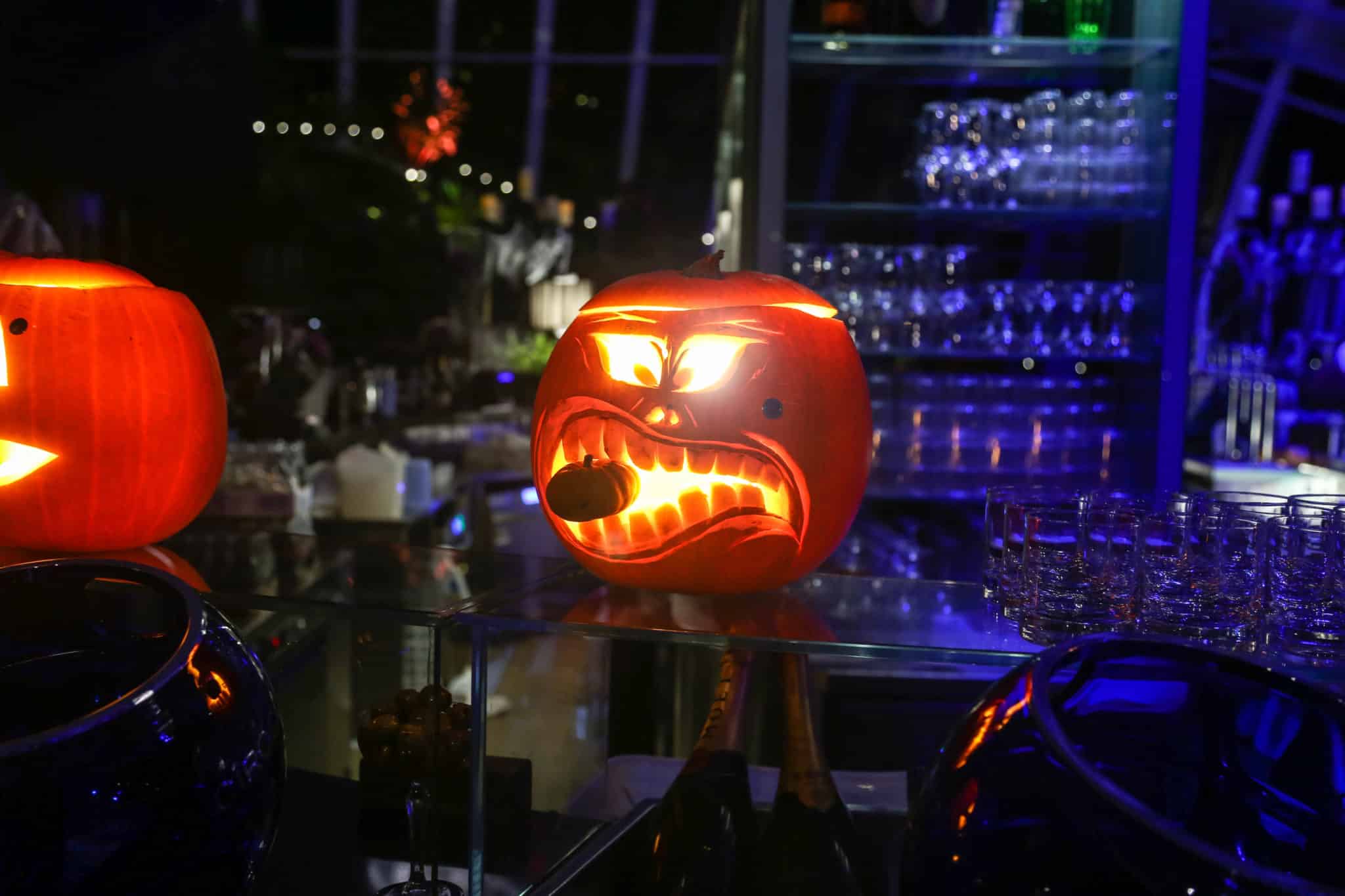 A halloween pumpkin with a smaller pumpkin perched between its carved teeth
