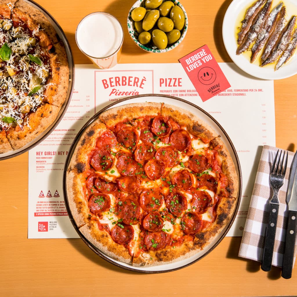 a pizza from Berberè Pizzeria, with a variety of other foodstuffs from the pizzeria scattered around