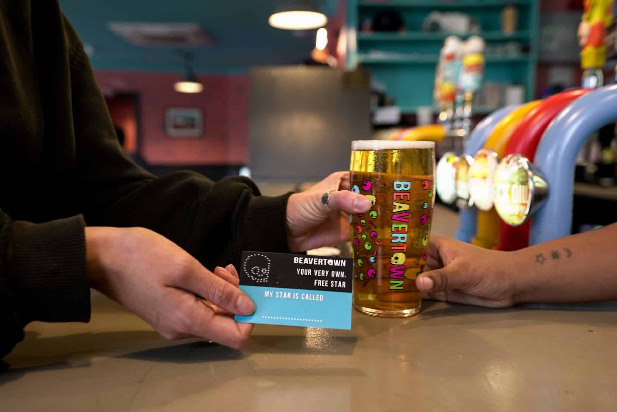 someone receiving a pint of beer and a star registration card