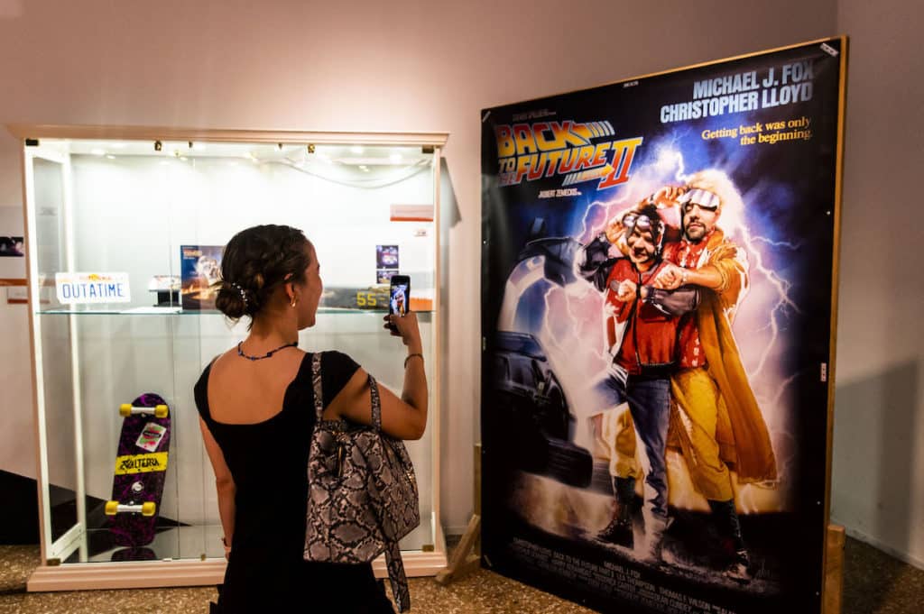 woman takes picture of people stick their faces through back to the future poster