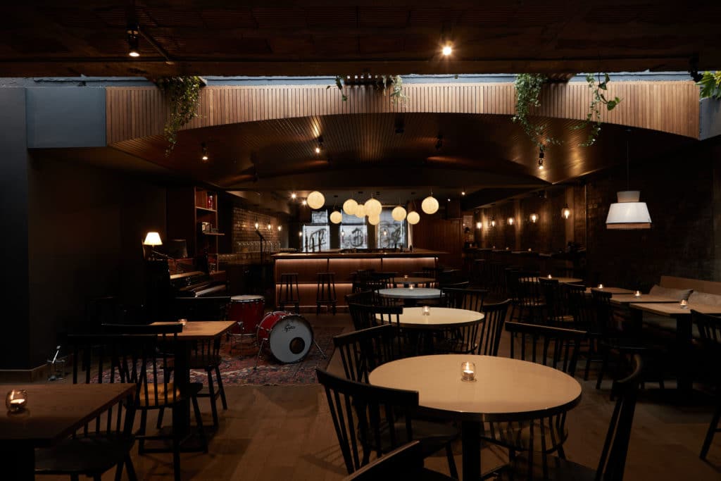 the interior of mu, with the band area visible, tables with candles on them, and the skylight above letting a bit of sunlight into the room