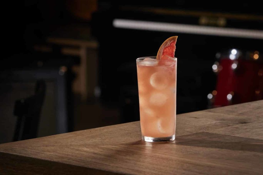 a palome in a tall glass, with a slice of grapefruit sticking out the top