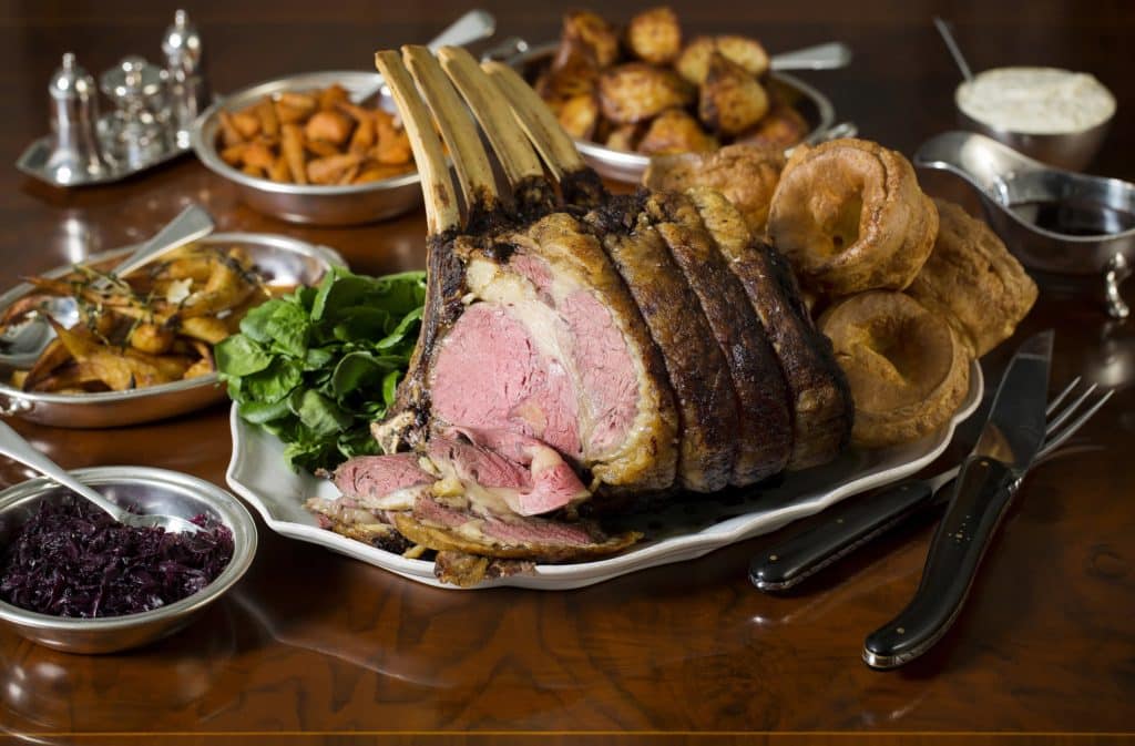 a shot of a plate of the roast beef from The Game Bird's Sunday Lunch, surrounded by yorkshire puddings, roast potatoes, and an assortment of other veggies