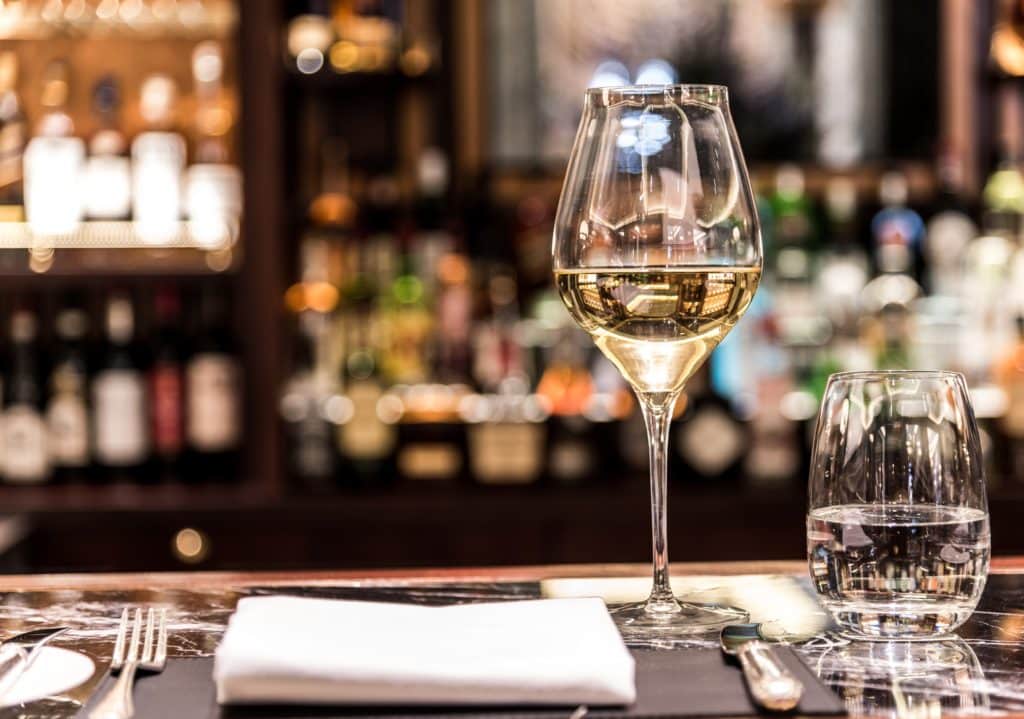 a glass of wine atop the table, with a napkin in front