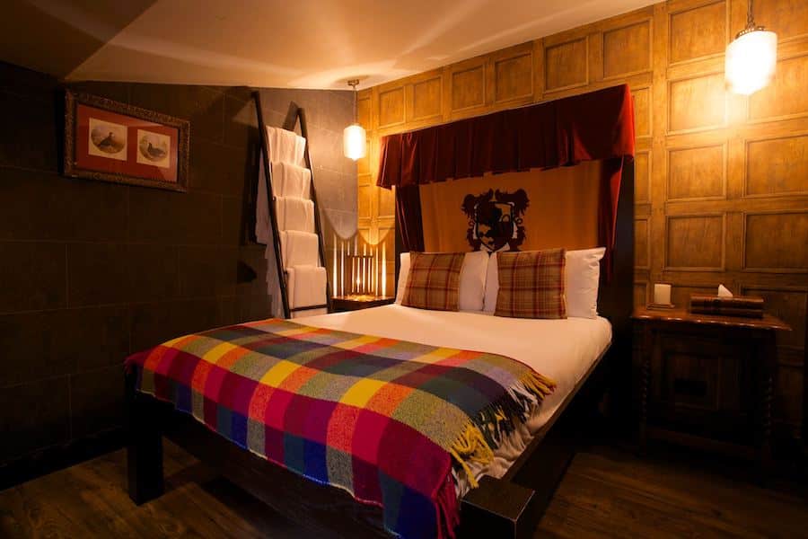 Bed draped in tartan blanket with Gryffindor symbol on headboard
