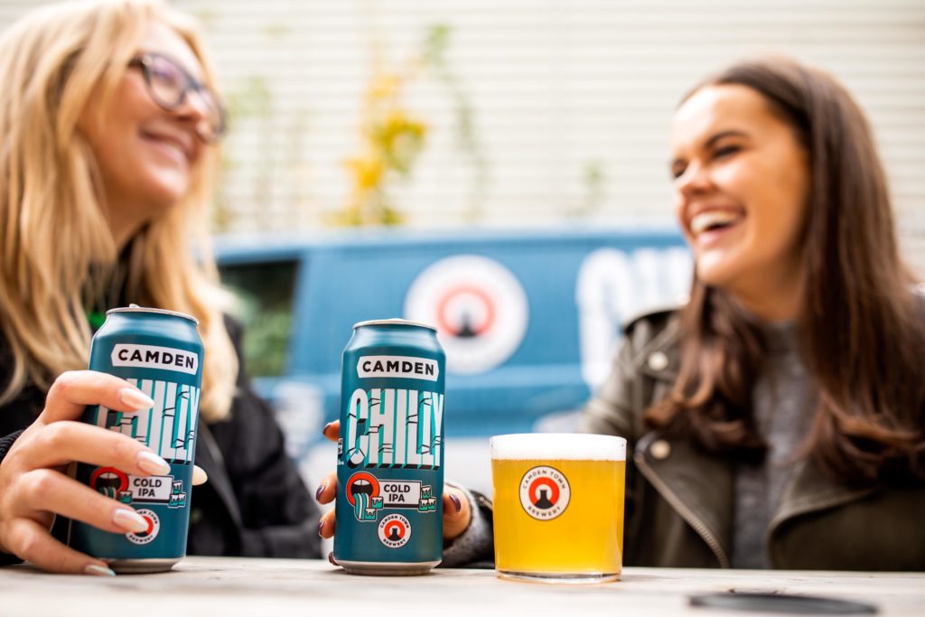 Two women sat with cans of camden chilly cold ipa
