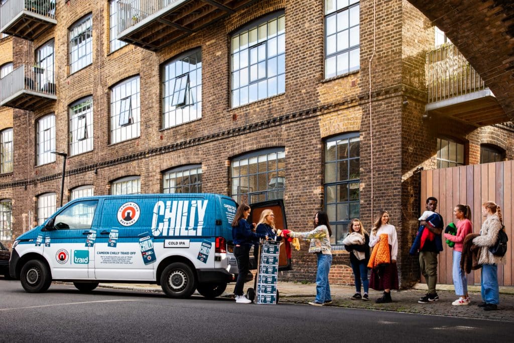 Line of people exchanging clothes for beer at camden chilly traid off van