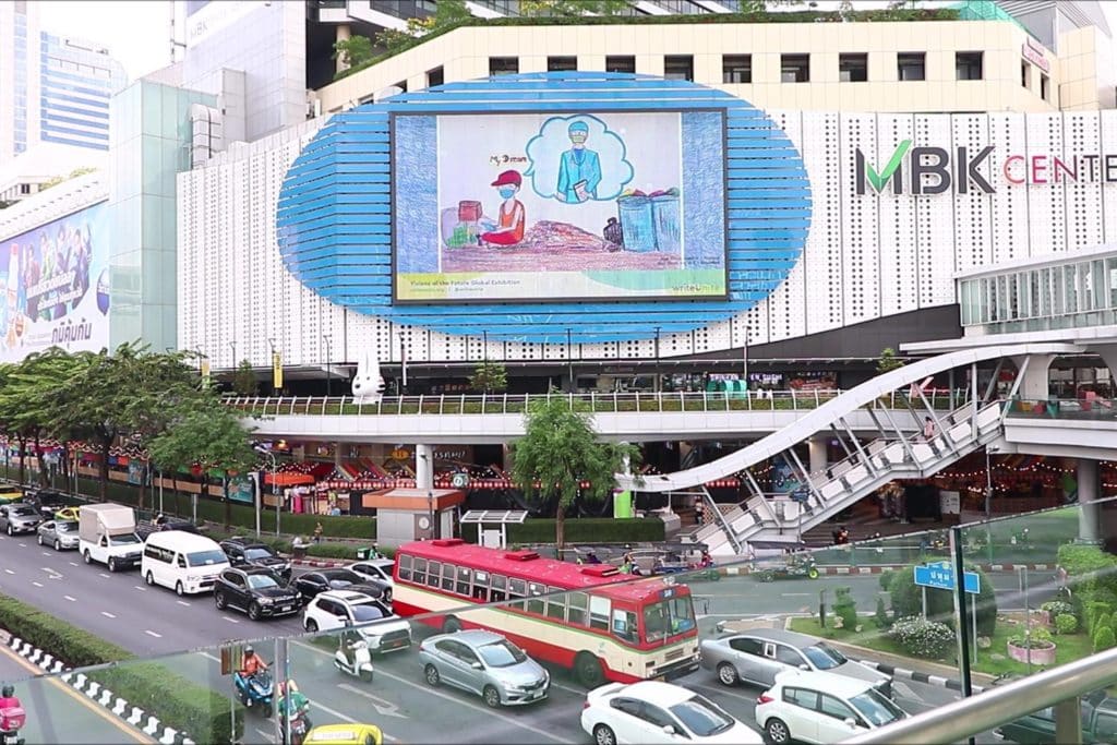 a billboard outside a shopping centre in Bangkok, showing artwork from the global exhibition visions of the future