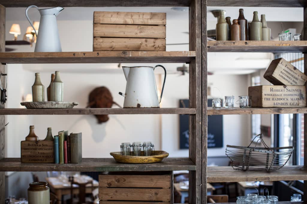 shelving in the pig and butcher dining room, with milk jugs and crates littered across it