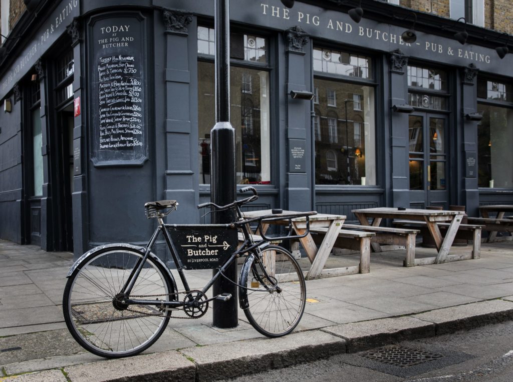 a bike, advertising the pig and butcher in a sign across its frame, parked outisde the pig and butcher
