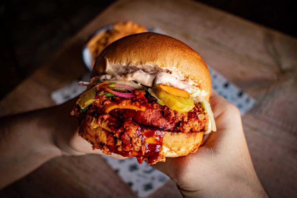 two hands holding the already messy sloppy faux burger from fat hippo