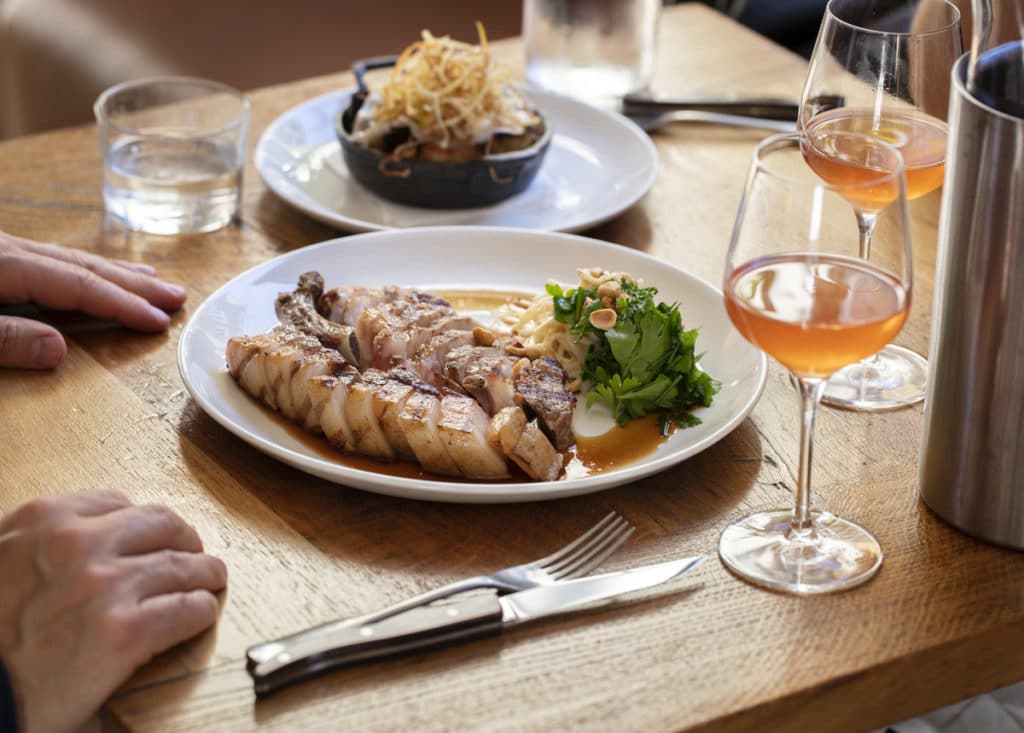 A delicious plate of pork and glasses of orange wine served at the Hicce Hart in Islington