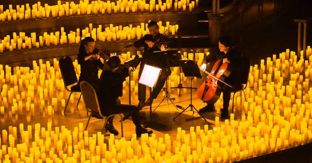 A string quartet performing amid a sea of candles