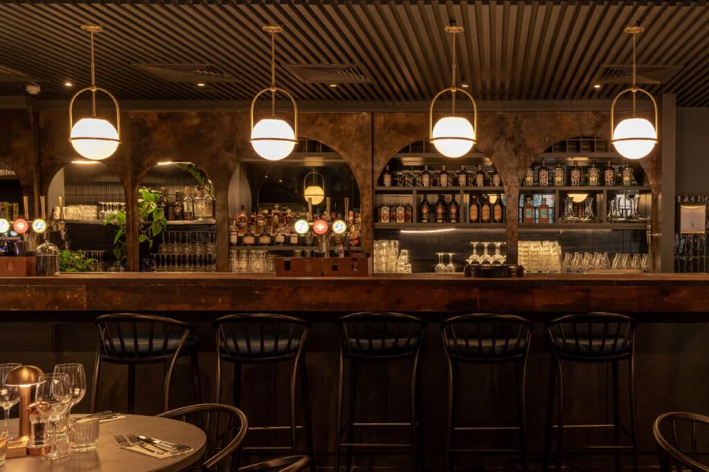 the polished wooden bar at KöD London, with a well-stocked display of liquors and spirits visible behind 