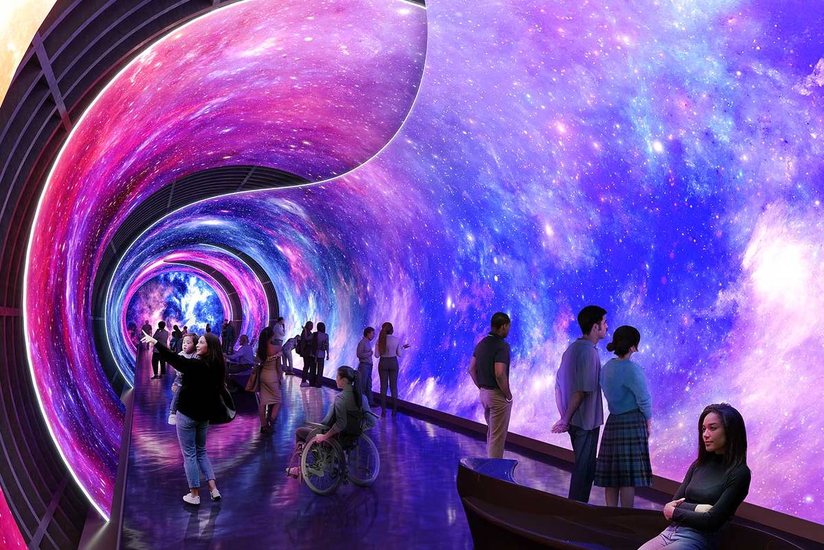 An underground tunnel with bright purple images of space projected onto the walls