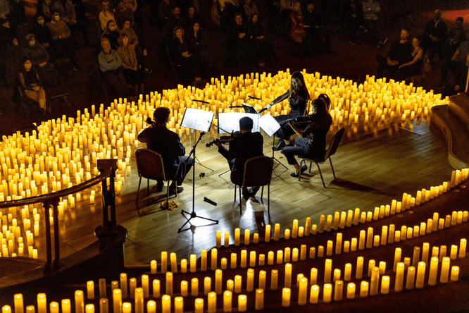 A string quartet performing amid a sea of candles