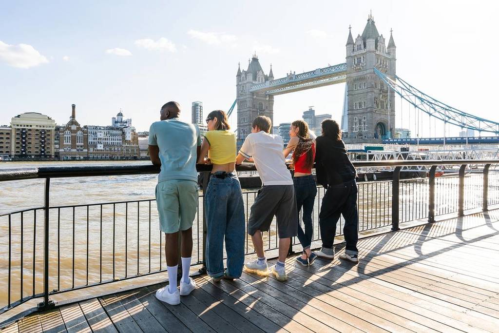 Groupe d'amis au bord de la Tamise avec vue sur le Tower Bridge.