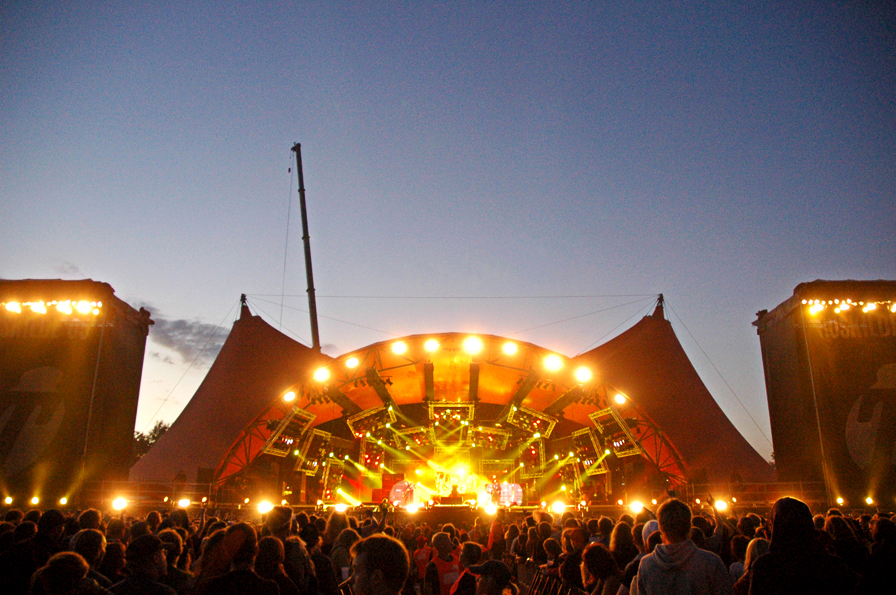 Main stage at Roskilde festival lit up with lights during sunset