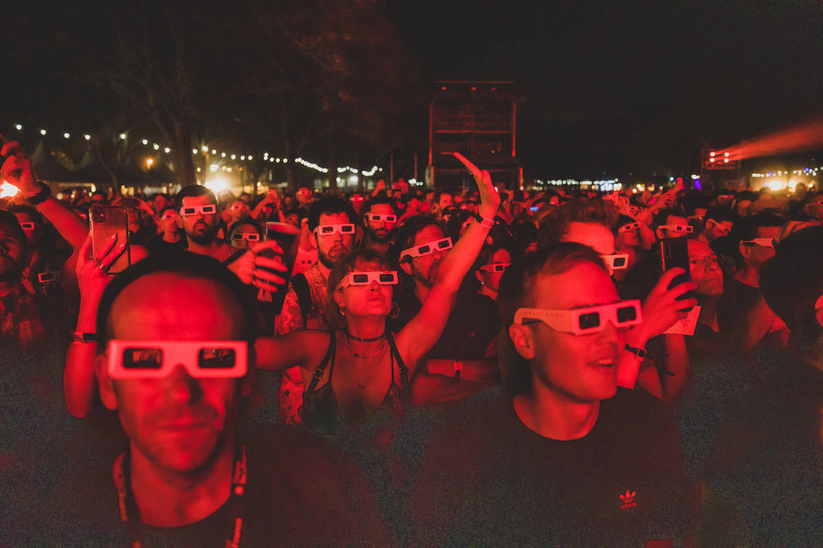 Crowd wearing 3D glasses and dancing at Rock En Seine Festival while red strobe lights flash