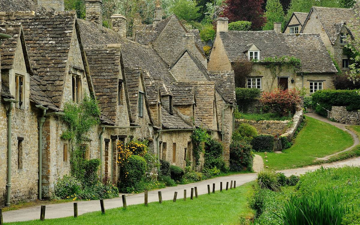 A row of old weavers' cottages on a country lane. There's another house in the distance, up a small hill.