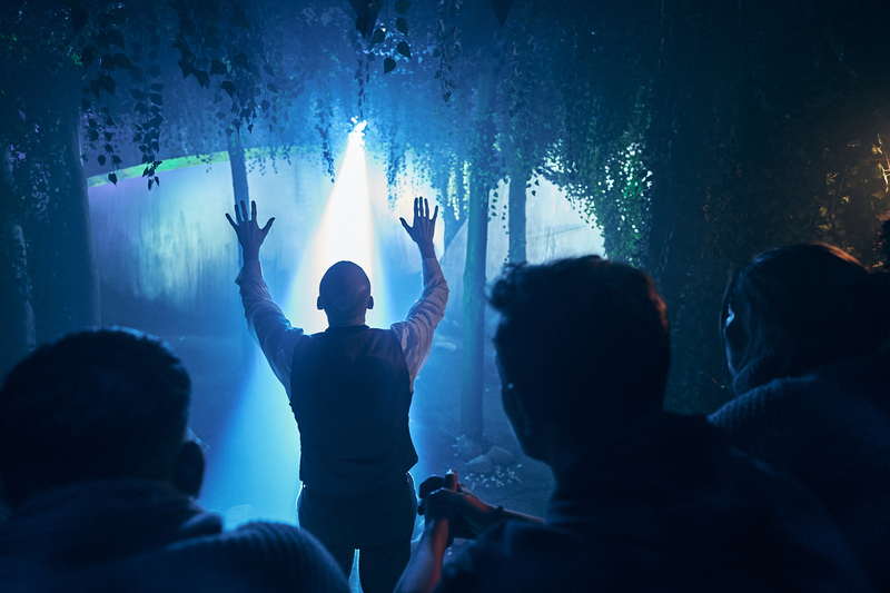 an actor with their hands raised as a martian scanning ray passes over them