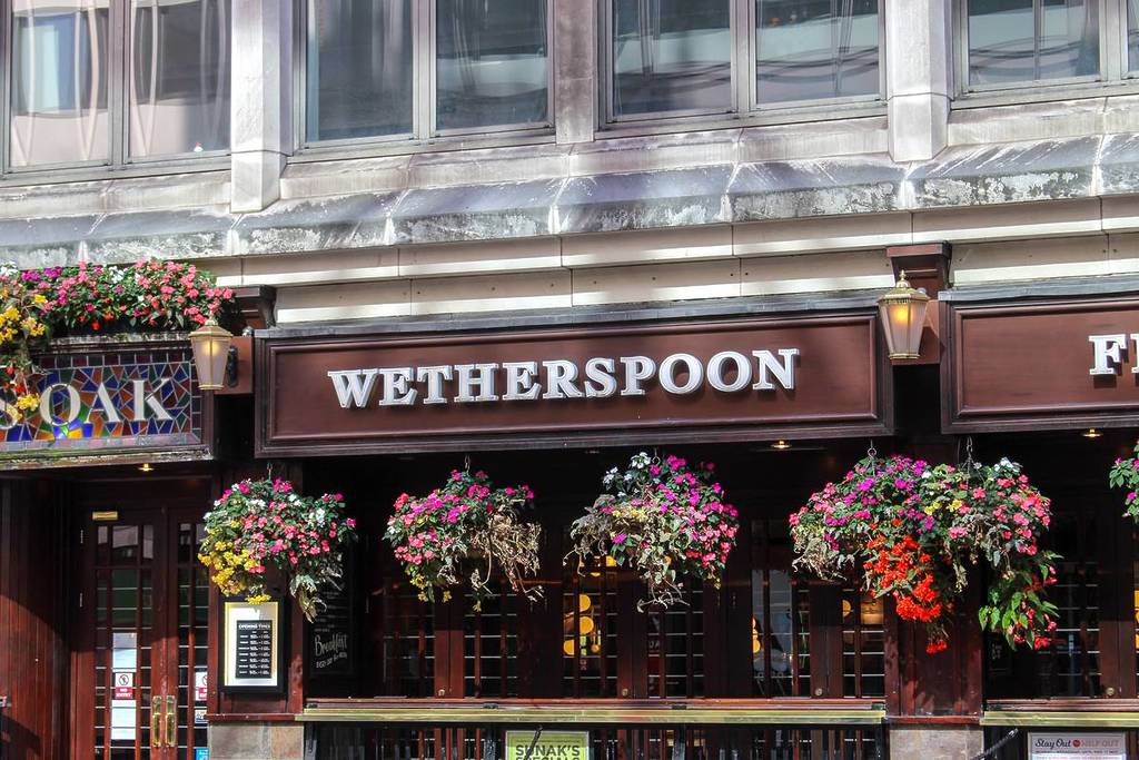 La fachada de un pub de Wetherspoons con cestas colgantes de flores que decoran la entrada